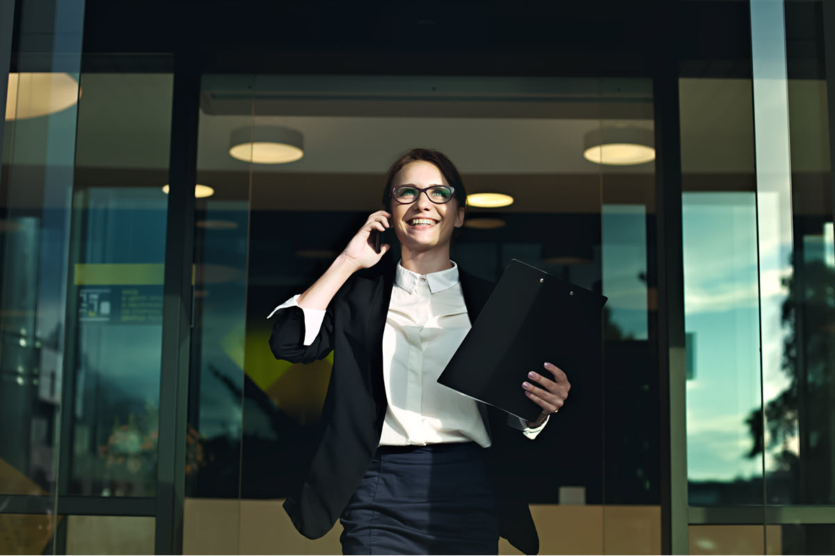 business woman exiting building on phone