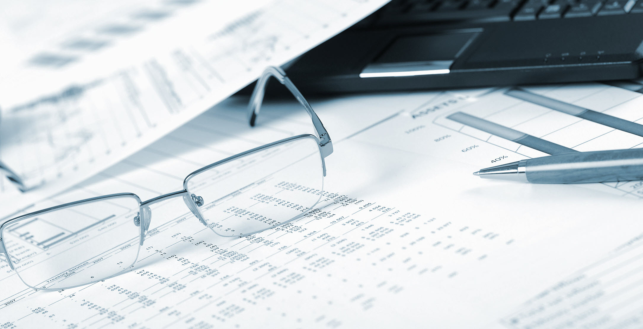 desk with reading glasses spreadsheet keyboard and pen email